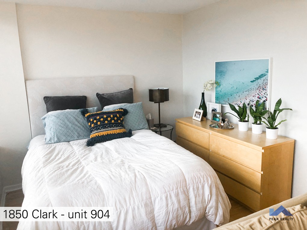 a bedroom with a bed and a dresser and potted plants